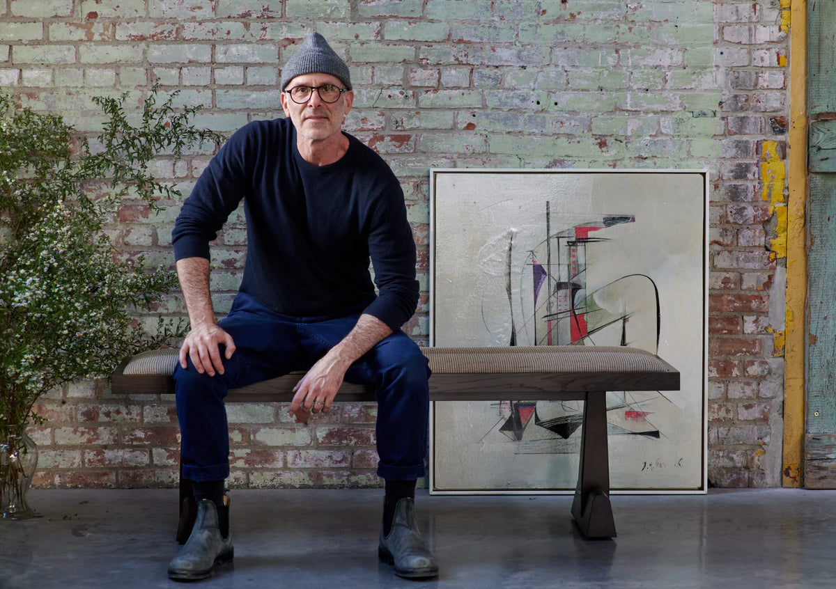 Seated on the FINCH AX Bench in front of a painted brick wall