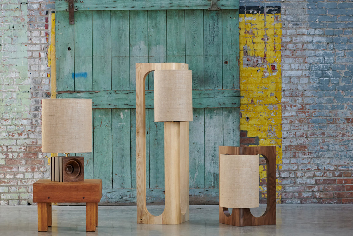 Prague Lighting desk, table and floor lamps in walnut and light oak against a painted brick wall