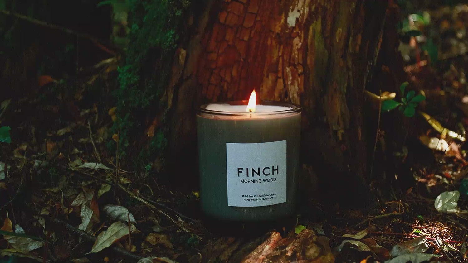FINCH Morning Wood candle burning on a mossy forest floor